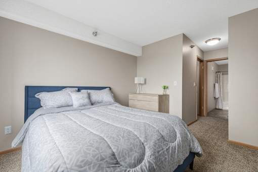 A bedroom with a large bed and a carpeted floor.