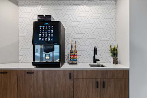 A black coffee machine is on a counter with a white background.