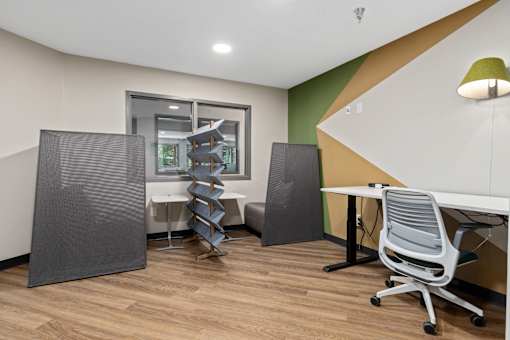 A room with a desk, chairs, and a window.
