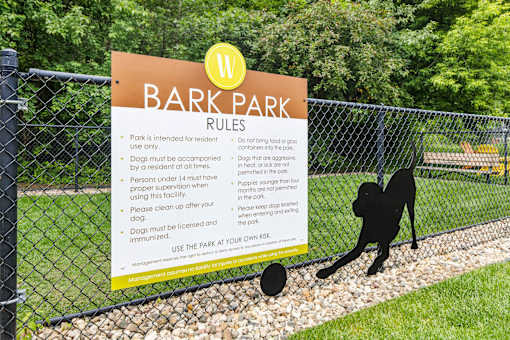 A sign for Bark Park rules is posted on a fence.