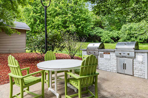 A white table with green chairs is in the middle of a patio.