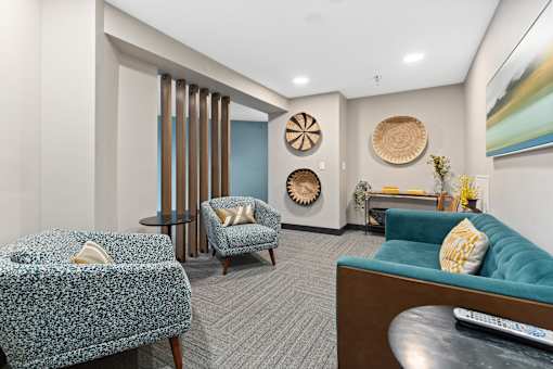 A living room with a blue couch and a patterned chair.
