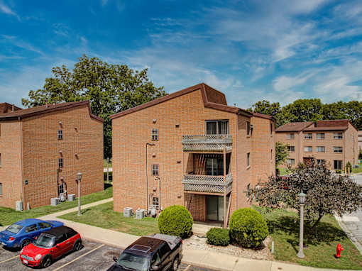 A parking lot with cars and a fire hydrant in front of a brick building.