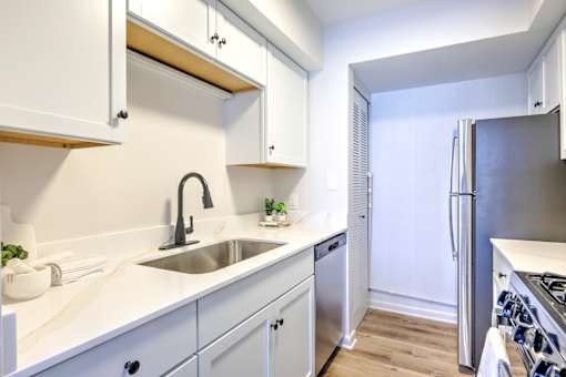A kitchen with white cabinets and a stainless steel refrigerator.