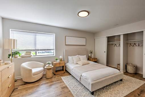 A bedroom with a large bed, a chair, and a nightstand.