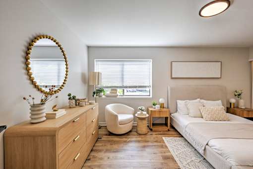 A bedroom with a large bed, a dresser, and a chair.