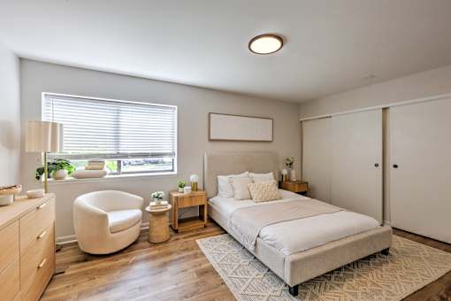 A bedroom with a large bed, a chair, and a nightstand.