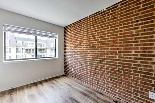 A room with a brick wall and a window overlooking a building.