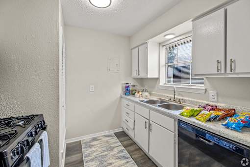 A kitchen with white cabinets and a black stove top oven. at La Bella Apartments, Fort Worth, TX