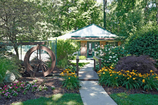 a garden with a mill wheel in front of a brick house