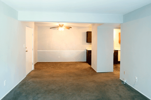 an empty room with a carpeted floor and a ceiling fan