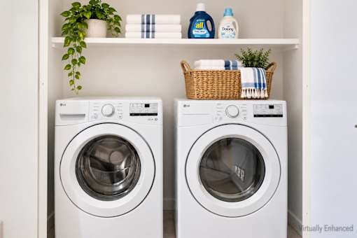 Two white front loading washing machines are placed in a cabinet.