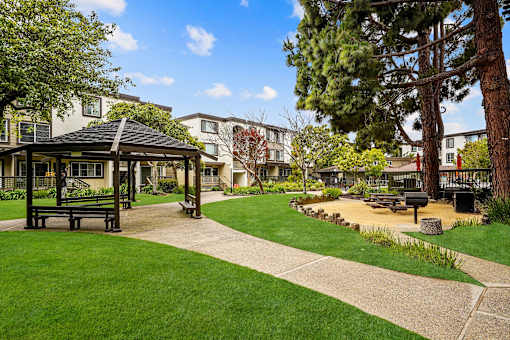 a park with a gazebo and benches in front of some apartments