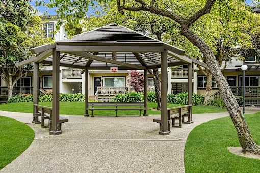 a park with a gazebo and benches in front of a building