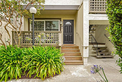 the front of a house with stairs and a black door