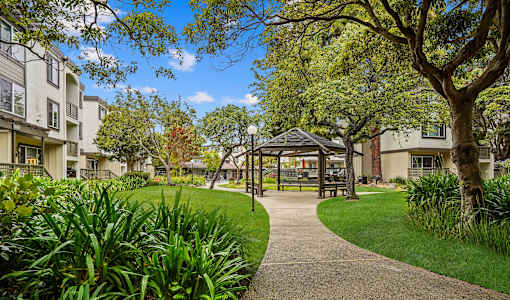 a park with a gazebo and trees in front of apartment buildings