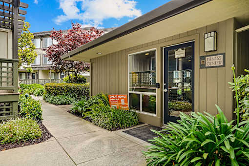 the entrance to an office building with a sidewalk and plants