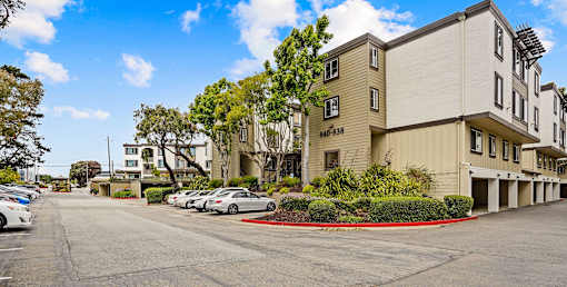 a street view of an apartment building with cars parked in front