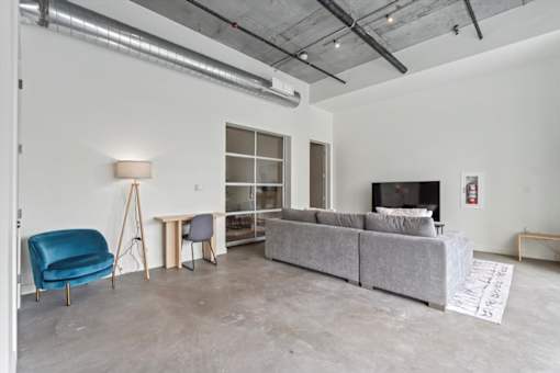 A living room with a grey couch, a blue chair, and a white floor lamp.
