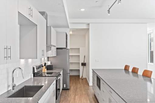 A modern kitchen with a sink, stove, and refrigerator.