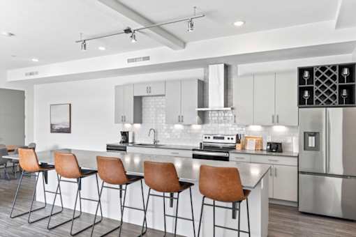 A modern kitchen with a bar area and chairs.