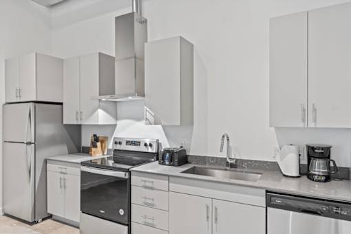 A modern kitchen with white cabinets and stainless steel appliances.