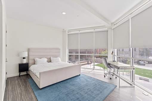 A bedroom with a large bed and a chair by the window.