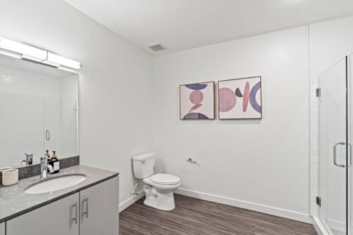 A bathroom with a toilet, sink, and two framed pictures on the wall.