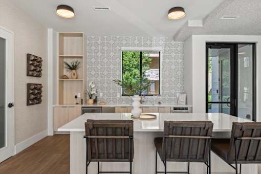 A kitchen with a white countertop and brown chairs.