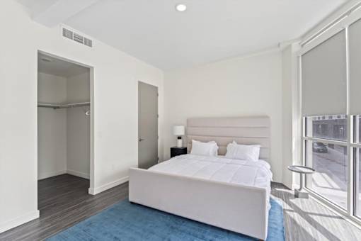 A bedroom with a large bed and a blue rug.