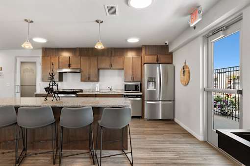 a kitchen with stainless steel appliances and a bar with four chairs at Red Rock Apartments, Rapid City