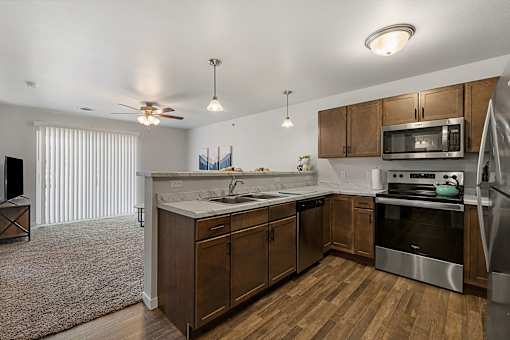 a kitchen with wooden cabinets and stainless steel appliances at Red Rock Apartments, Rapid City, SD