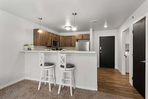 a kitchen with a bar and two stools in front of a counter top at Red Rock Apartments, Rapid City