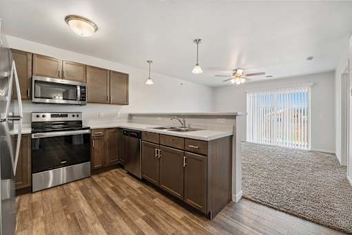 a kitchen with wooden cabinets and stainless steel appliances at Red Rock Apartments, South Dakota