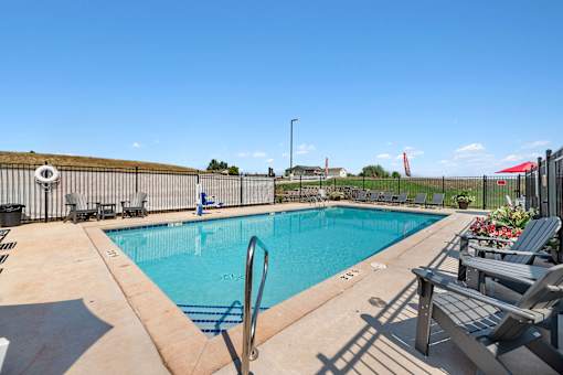 a swimming pool with chairs and a fence around it at Red Rock Apartments, South Dakota 57702