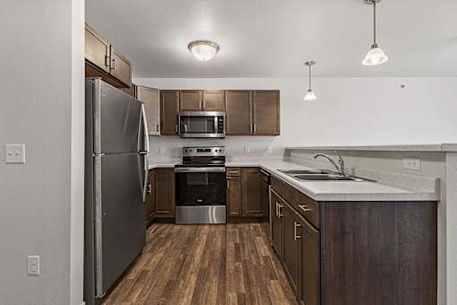 an empty kitchen with stainless steel appliances and wooden cabinets at Red Rock Apartments, Rapid City