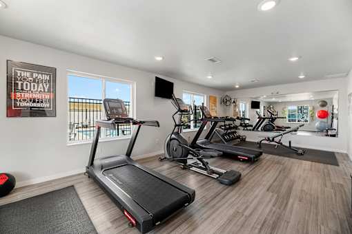 two treadmills and other exercise equipment in a gym with windows at Red Rock Apartments, Rapid City