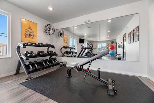a home gym with weights and mirrors and a large mirror on the wall at Red Rock Apartments, South Dakota