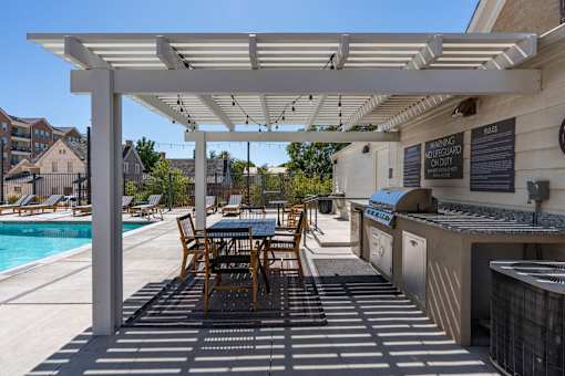 a patio with a grill and a table with chairs and a pool at City View St. George Apartments, St George, UT, 84770