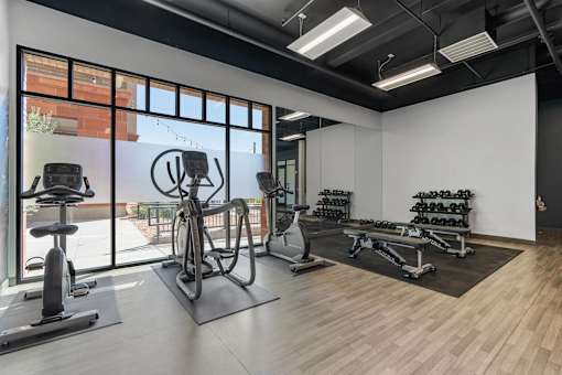 a gym with weights and other exercise equipment and a large window at City View St. George Apartments, St George, UT