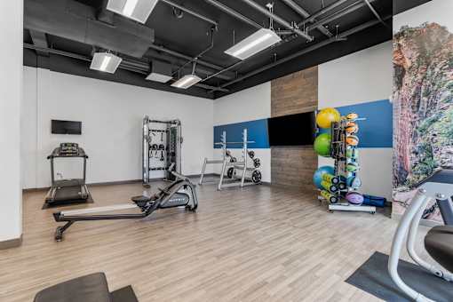 a gym with weights and exercise equipment and a wall with a colorful painting at City View St. George Apartments, St George