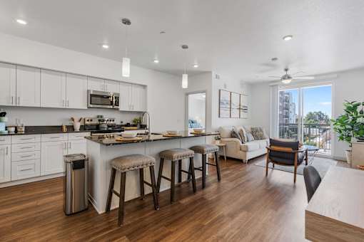 an open kitchen and living room with a large island and stools at City View St. George Apartments, St George, UT, 84770