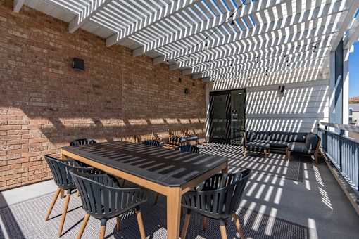 a patio with a wooden table and chairs and a brick wall at City View St. George Apartments, Utah