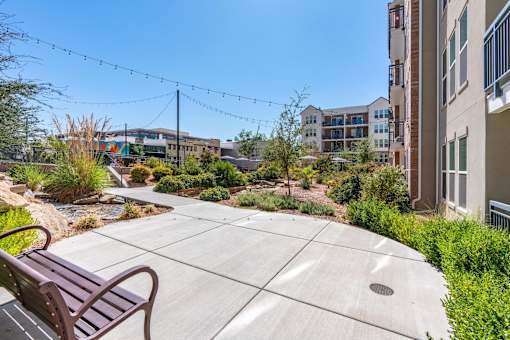 an outdoor patio with benches and plants in a building with other buildings at City View St. George Apartments, St George, UT, 84770