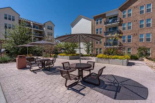 a patio with tables and umbrellas in front of an apartment building at City View St. George Apartments, St George, UT