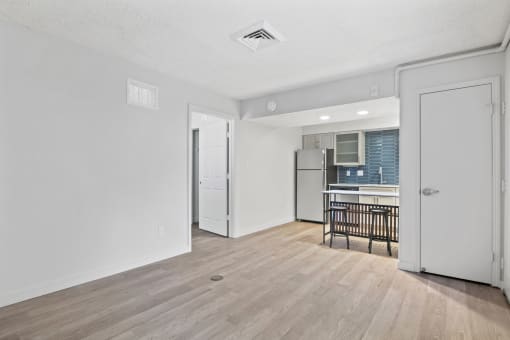 the living room and kitchen of an apartment with a hardwood floor and white walls at AVIA Lofts on Liberty Ridge, Jacksonville, FL, 32256