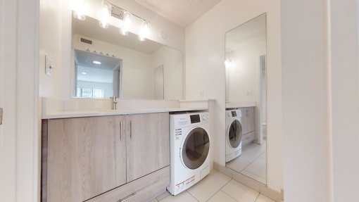 a washer and dryer in a laundry room with a sink and a mirror