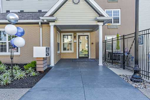 A building entrance with a black fence and blue and white balloons.