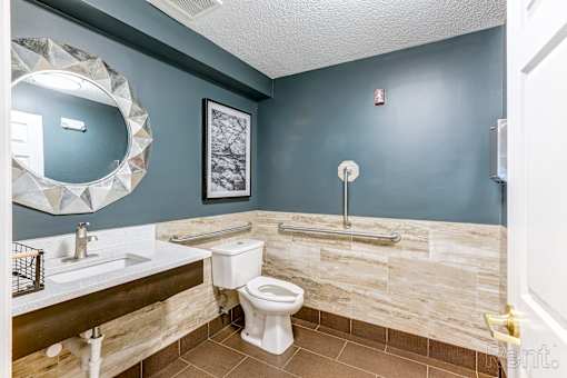 A bathroom with a toilet, sink, and mirror.