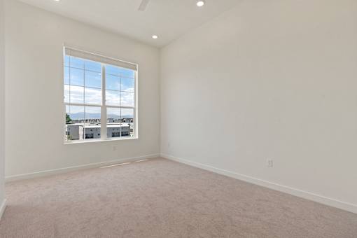 A large empty room with a window overlooking a cityscape.